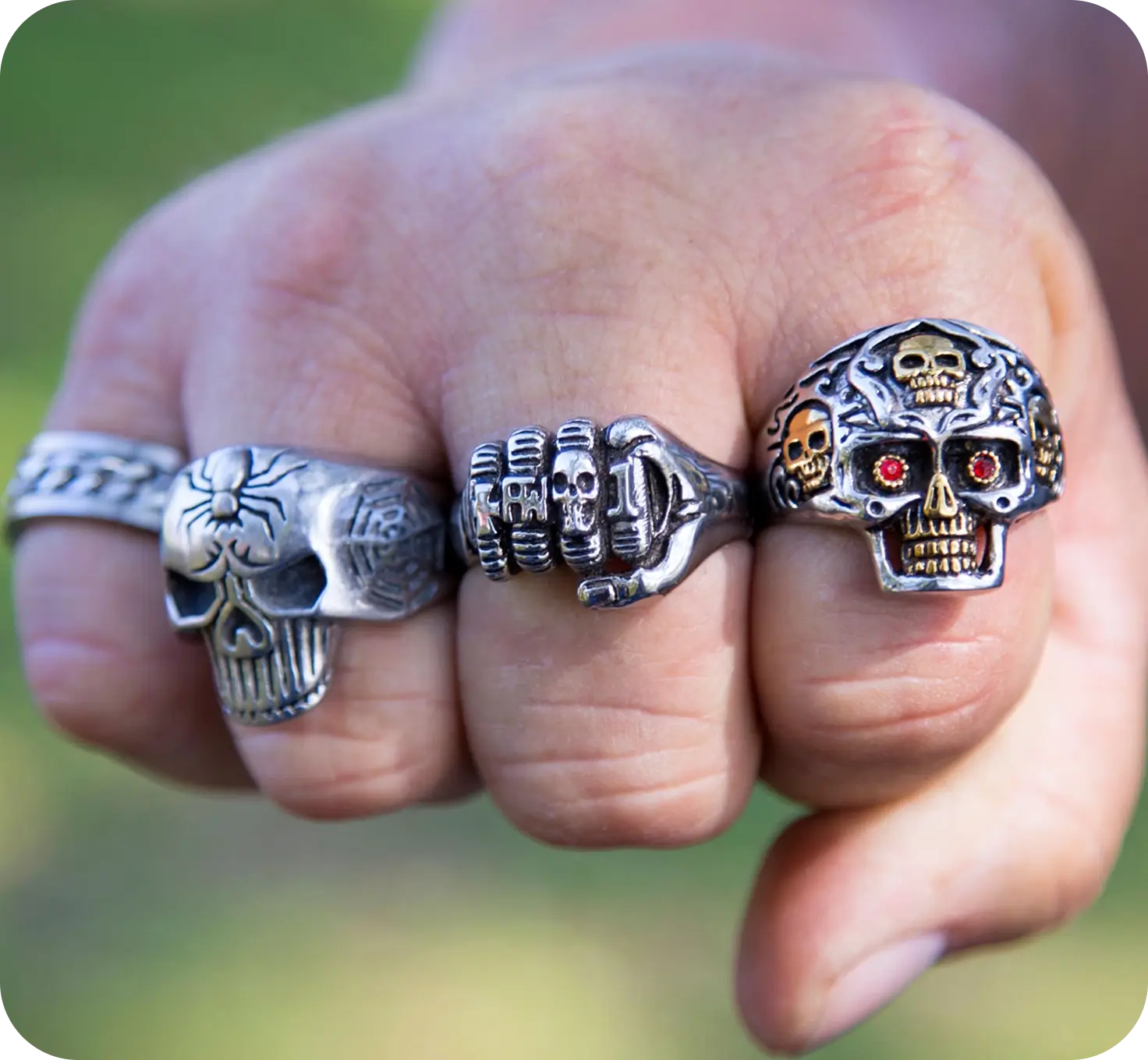 Fist displaying three ornate skull rings.