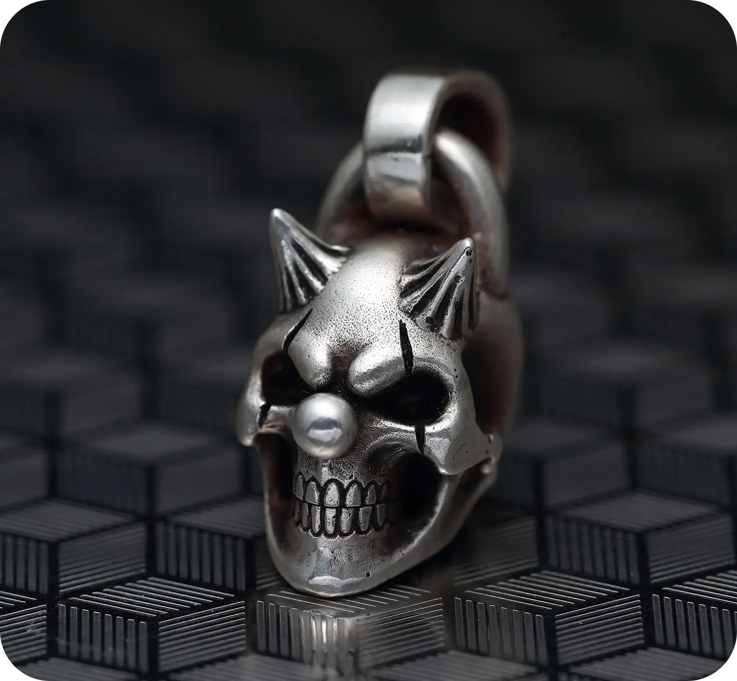 Silver skull pendant on textured surface.