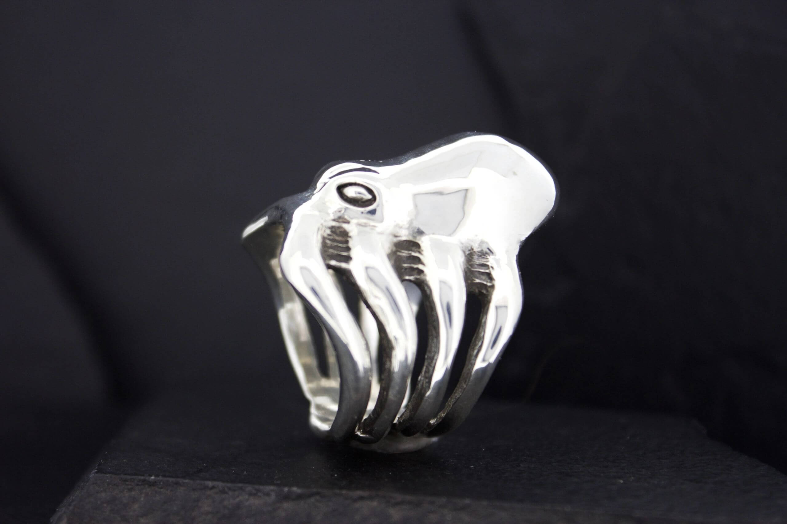A silver ring shaped like a hand with detailed fingers.