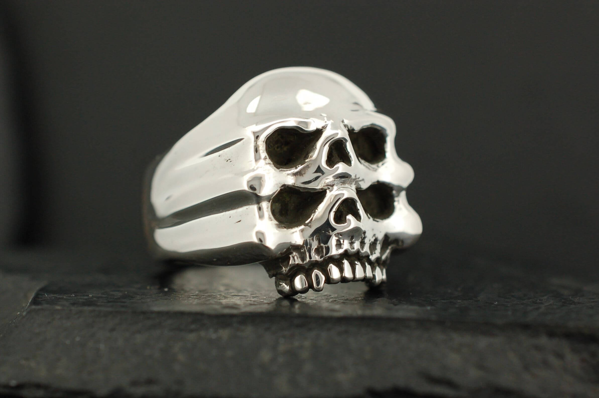 Silver ring with two stacked skull designs.