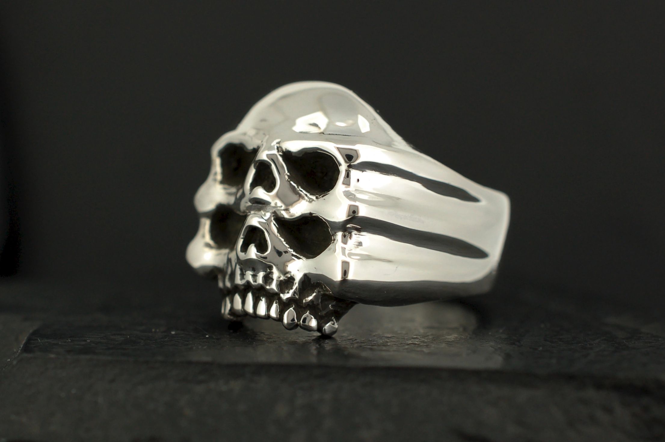A silver ring shaped like a detailed skull with hollow eyes and nose.