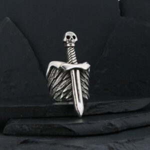 A silver dagger with a skull-shaped handle on a dark background.