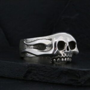 Silver skull ring with detailed design on black background.