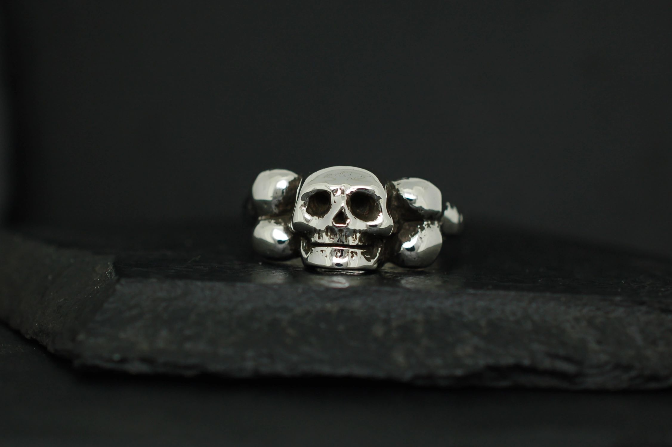 Silver skull ring with a dark background.