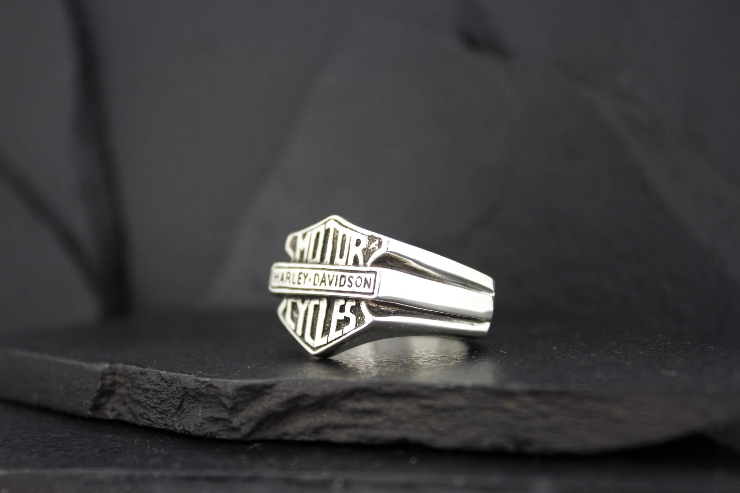 Silver ring featuring the Harley-Davidson logo on a dark background.