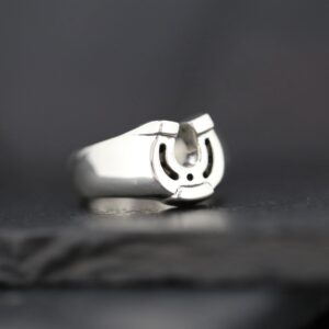 Close-up of a silver horseshoe ring on a dark surface.