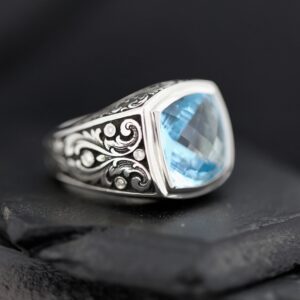 Elegant silver ring with intricate designs and a blue gemstone.