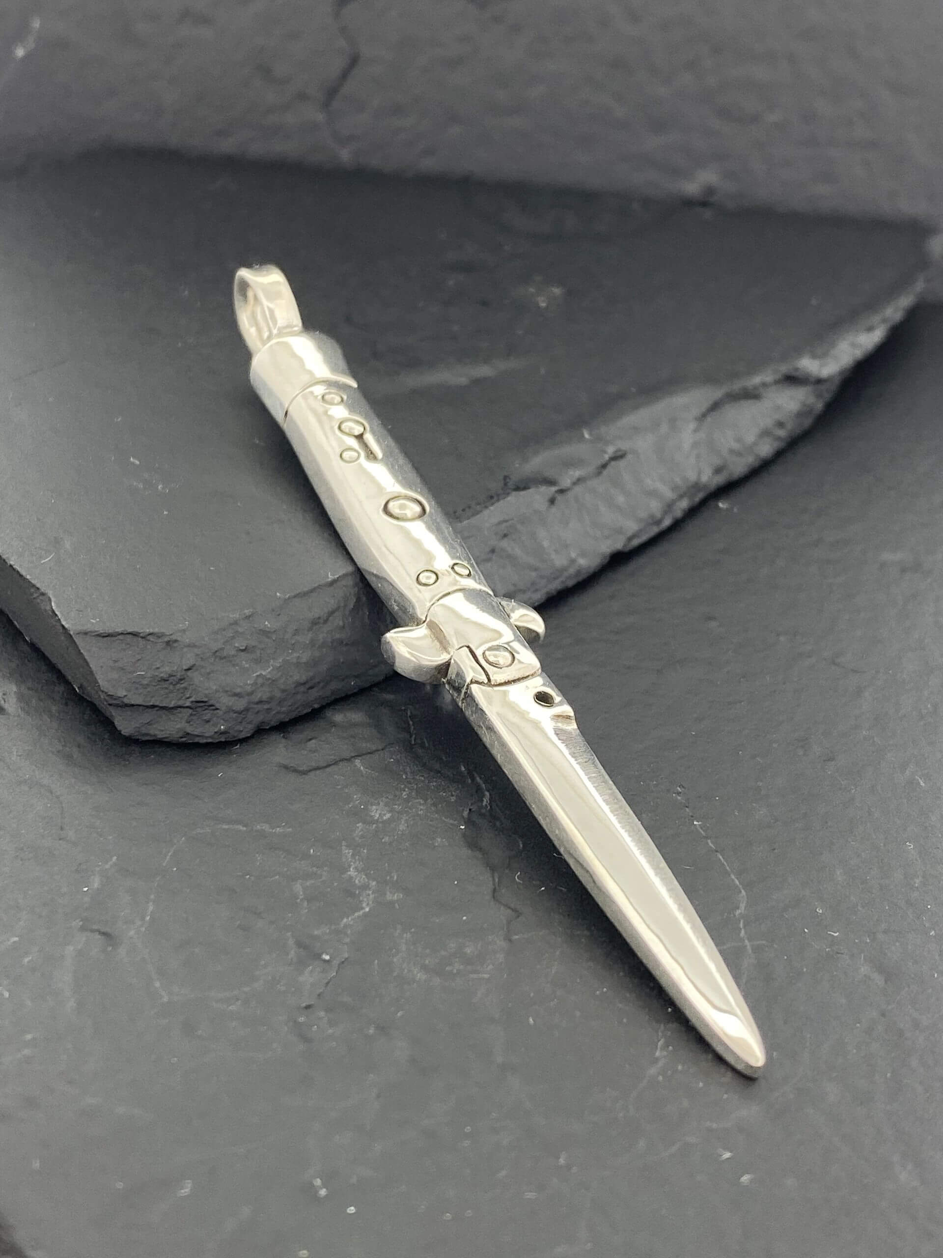 A silver decorative pen with intricate designs on a dark surface.