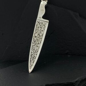 A silver knife-shaped pendant with intricate floral engravings.