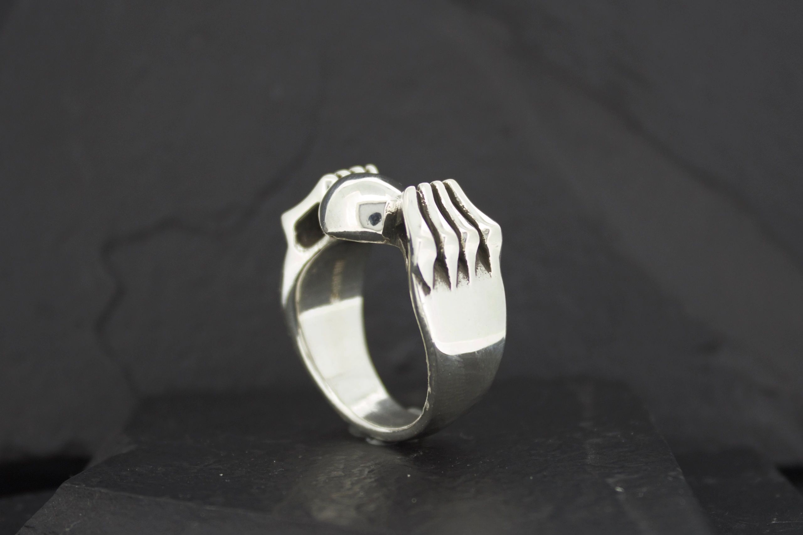 A silver ring designed like a hand gripping.