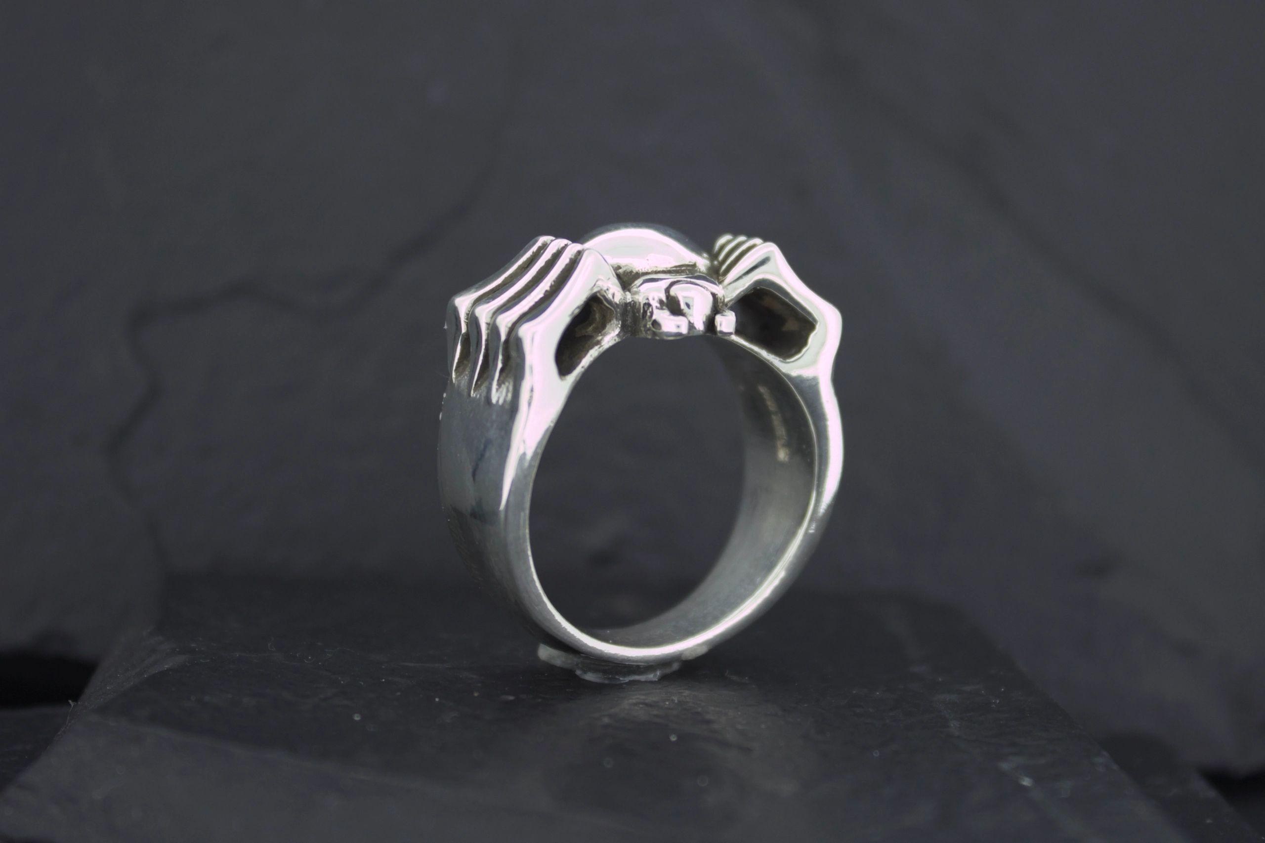 Silver ring shaped like two hands forming a heart.