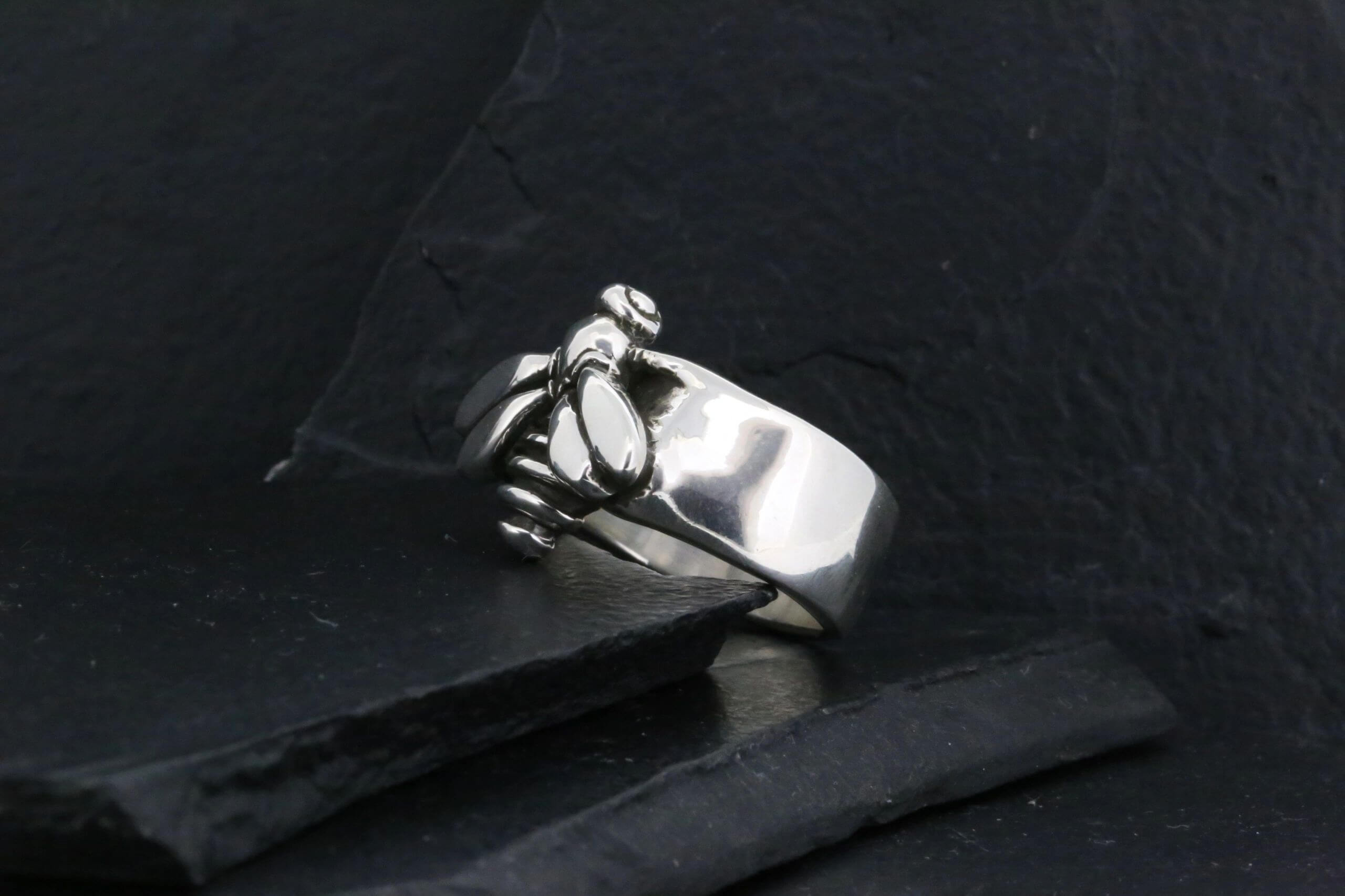 Silver ring with a unique claw-like design on a dark surface.