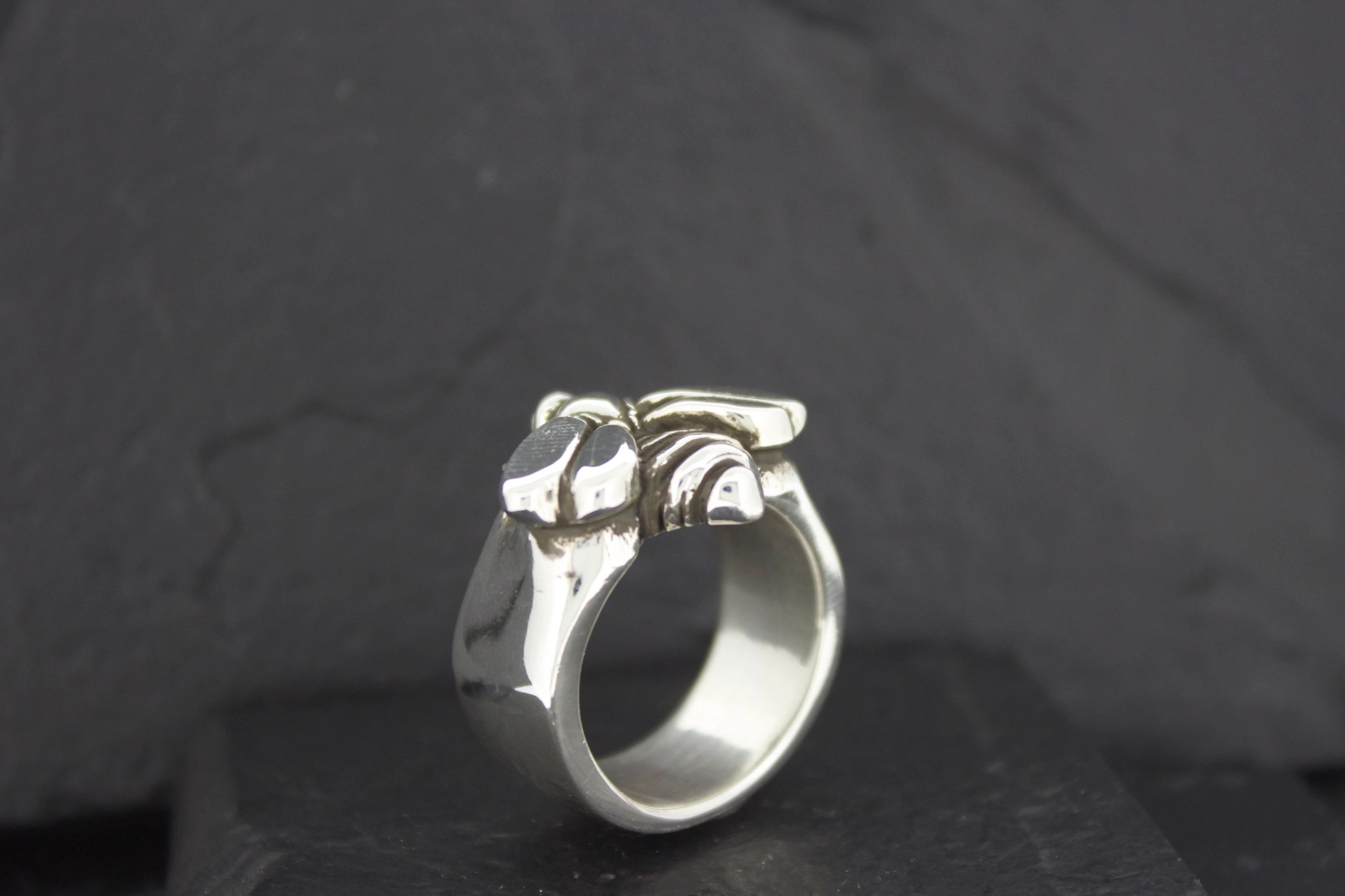 Silver ring designed with an elephant motif on a black background.