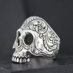 Intricately designed silver skull ring with ornate patterns.