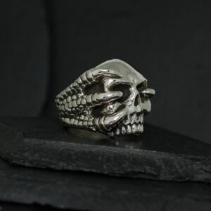 Intricately designed skull ring with claw details on a dark background.