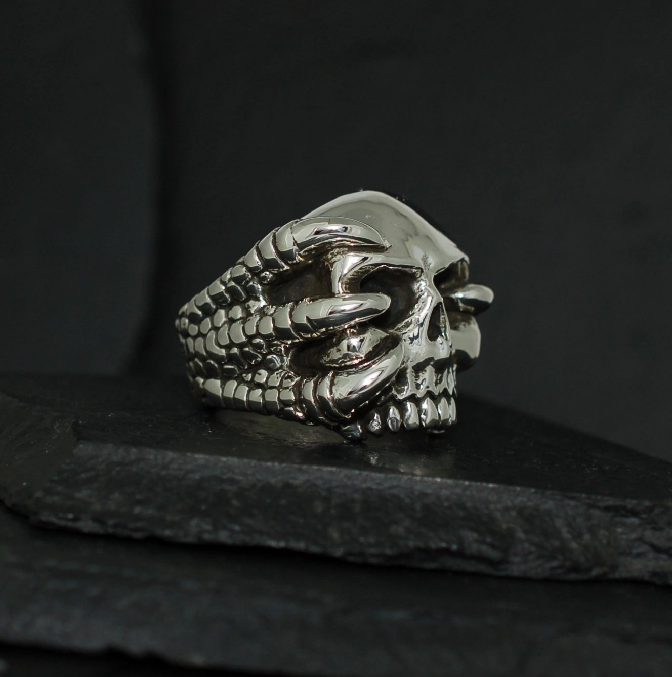 Intricately designed skull ring with claw details on a dark background.