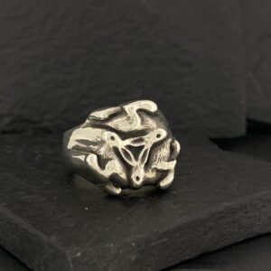 A shiny metallic abstract sculpture on a dark surface.
