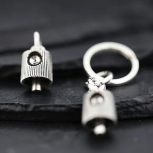 Close-up of a silver keychain with a small pendant on a dark surface.