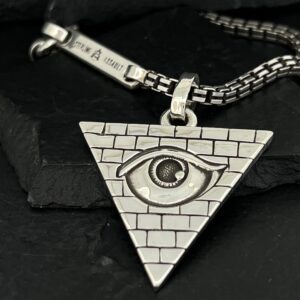 Triangle pendant with an eye and brick pattern on a silver chain.