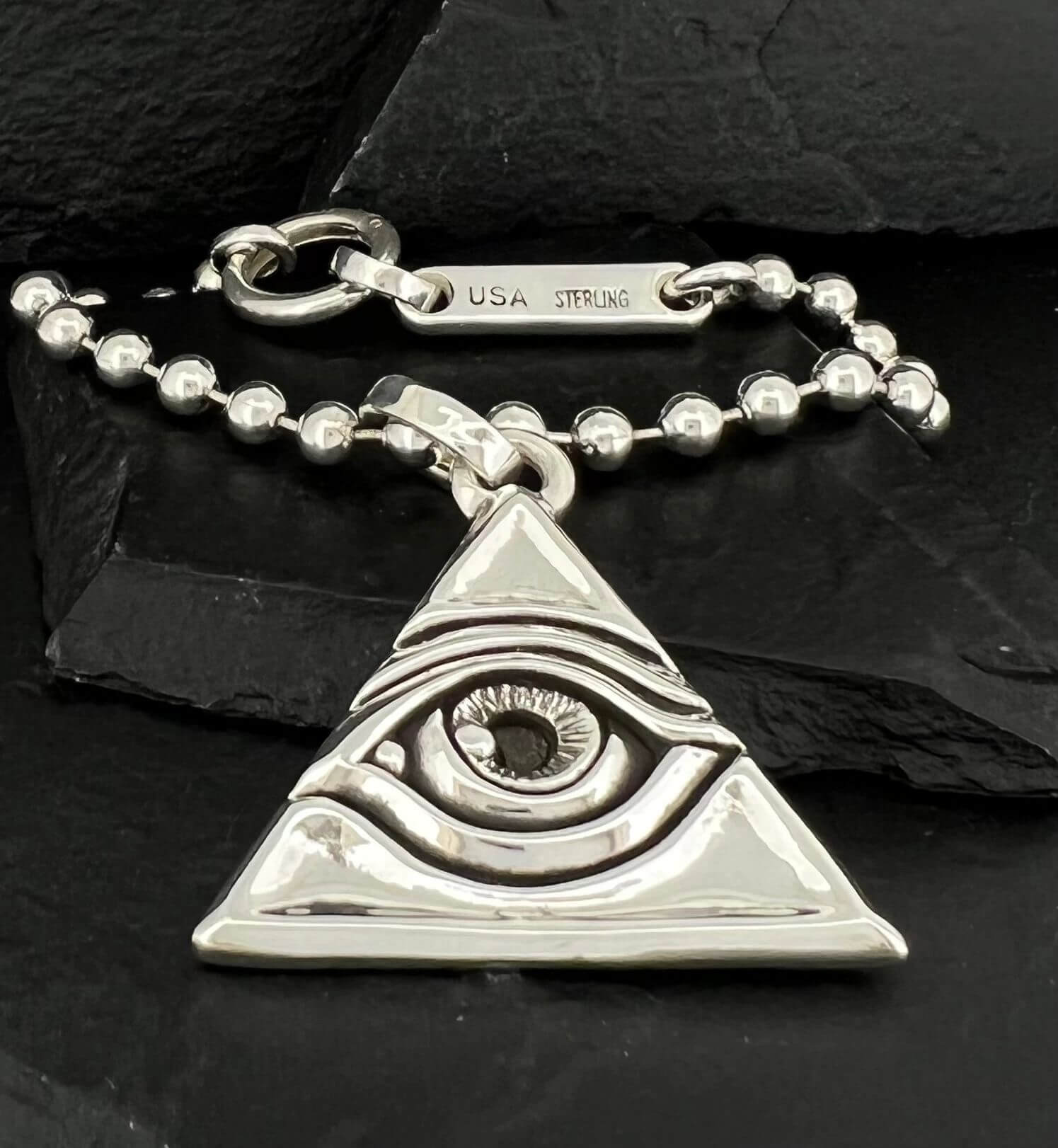 Silver keychain with an eye inside a triangle design.
