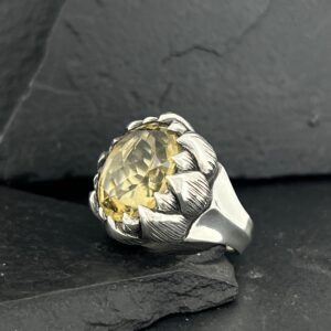 A silver ring with a large yellow gemstone, styled like a flower.