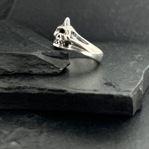 Elegant silver ring with a unique intertwined design on a dark slate surface.