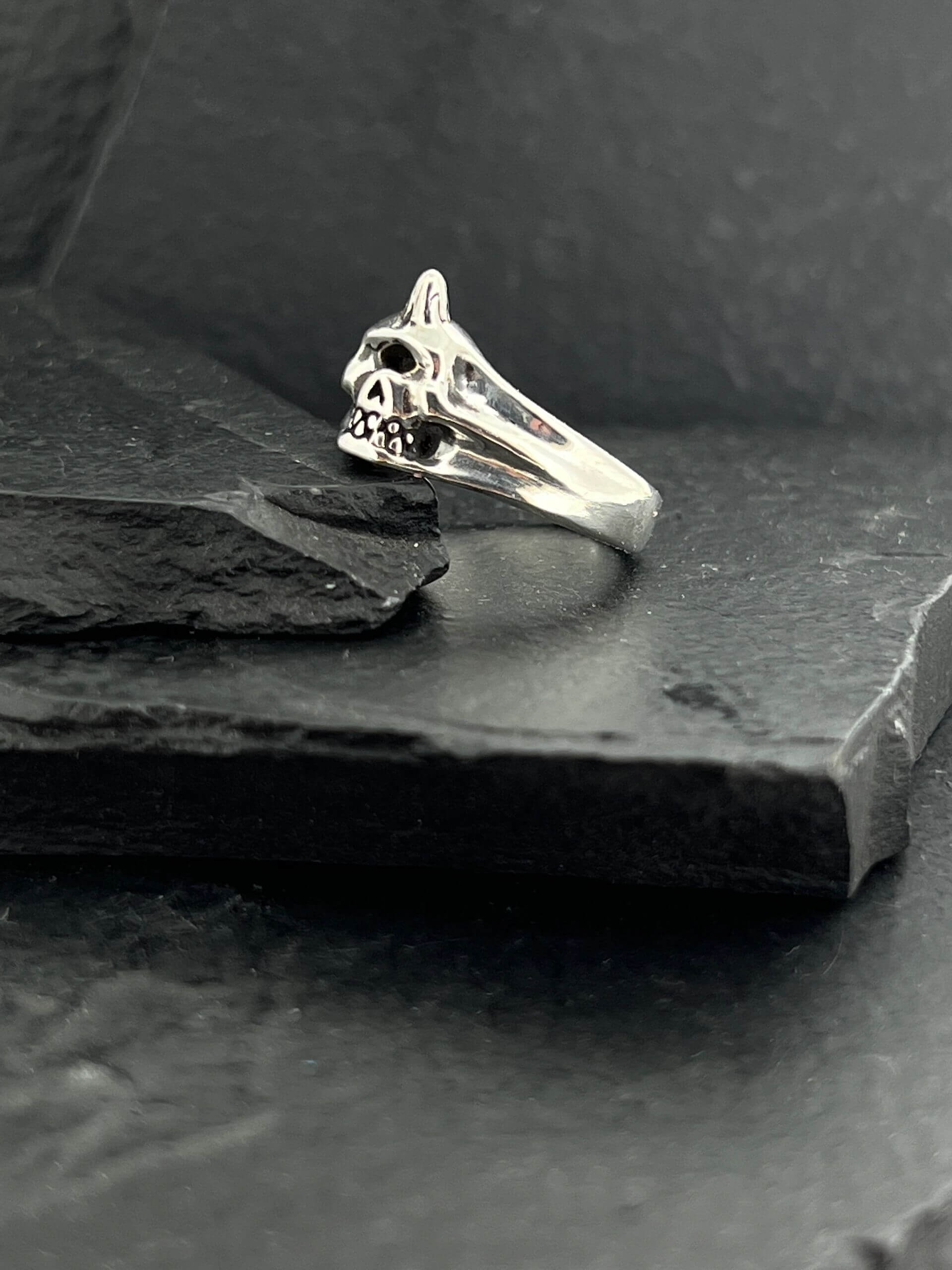 Elegant silver ring with a unique intertwined design on a dark slate surface.