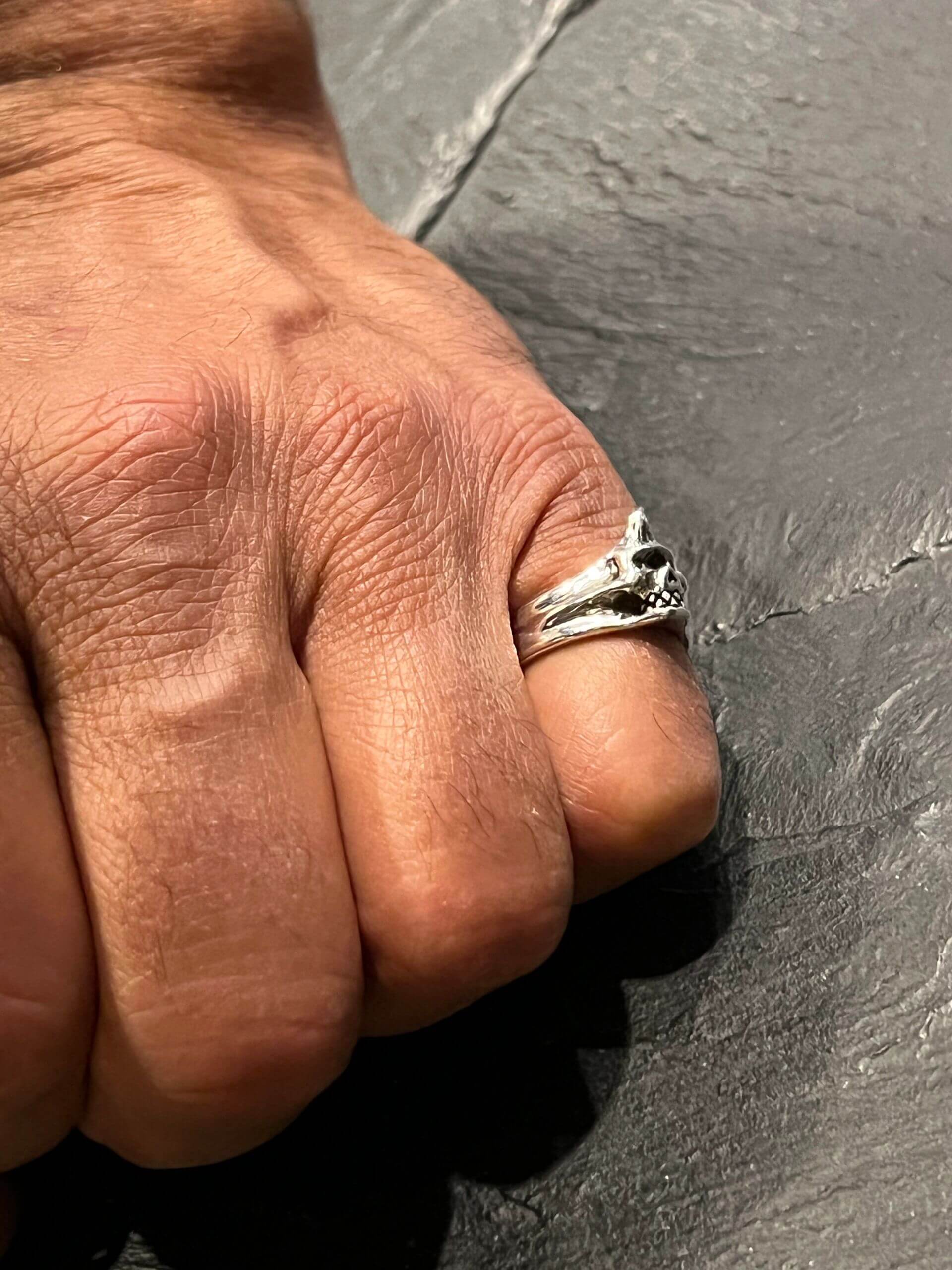 Close-up of a hand wearing a silver ring on the middle finger.
