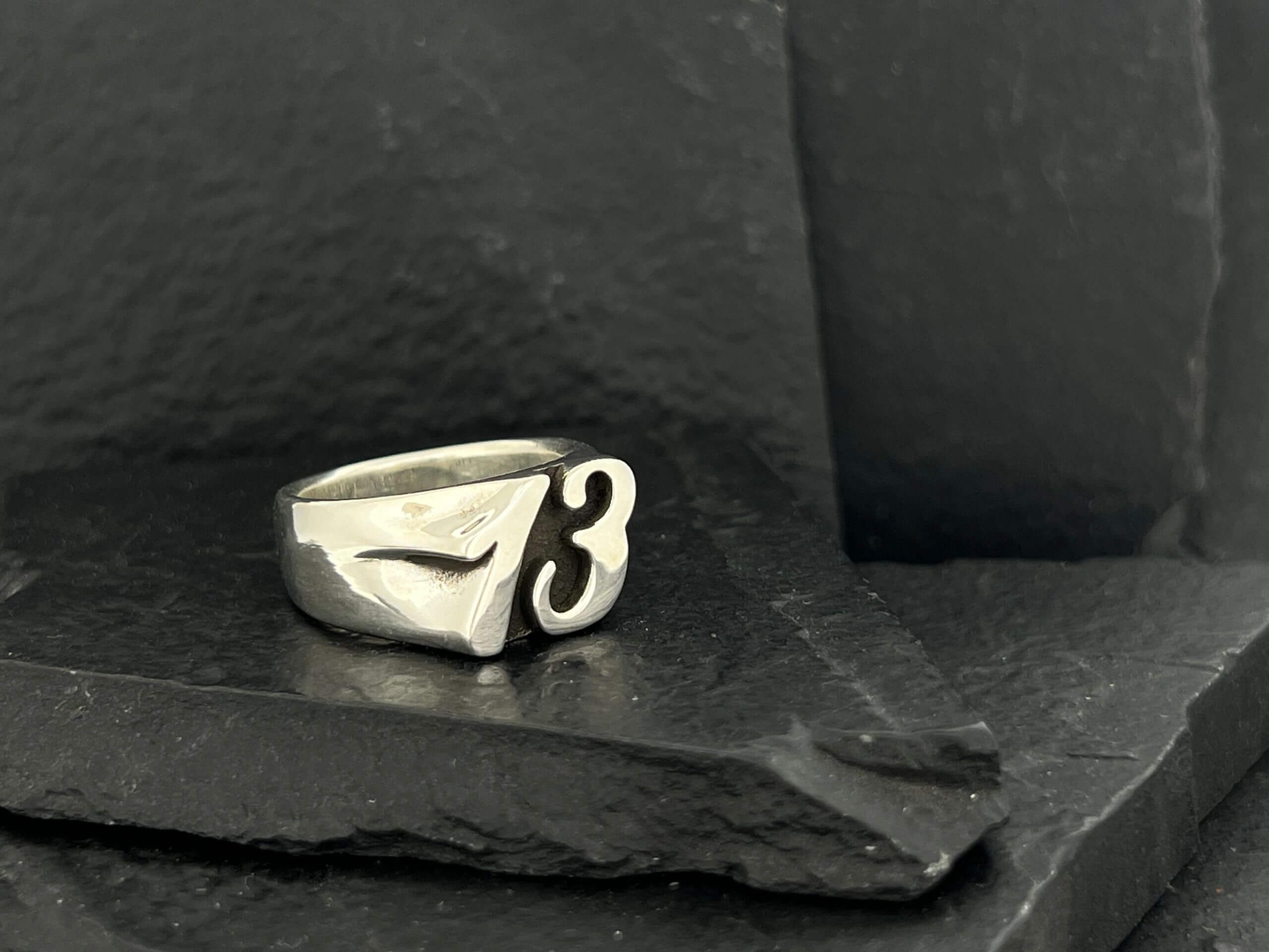 A silver ring with a unique design and the number 3.