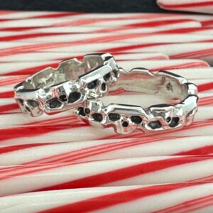 Two silver skull-themed rings on red and white striped surface.