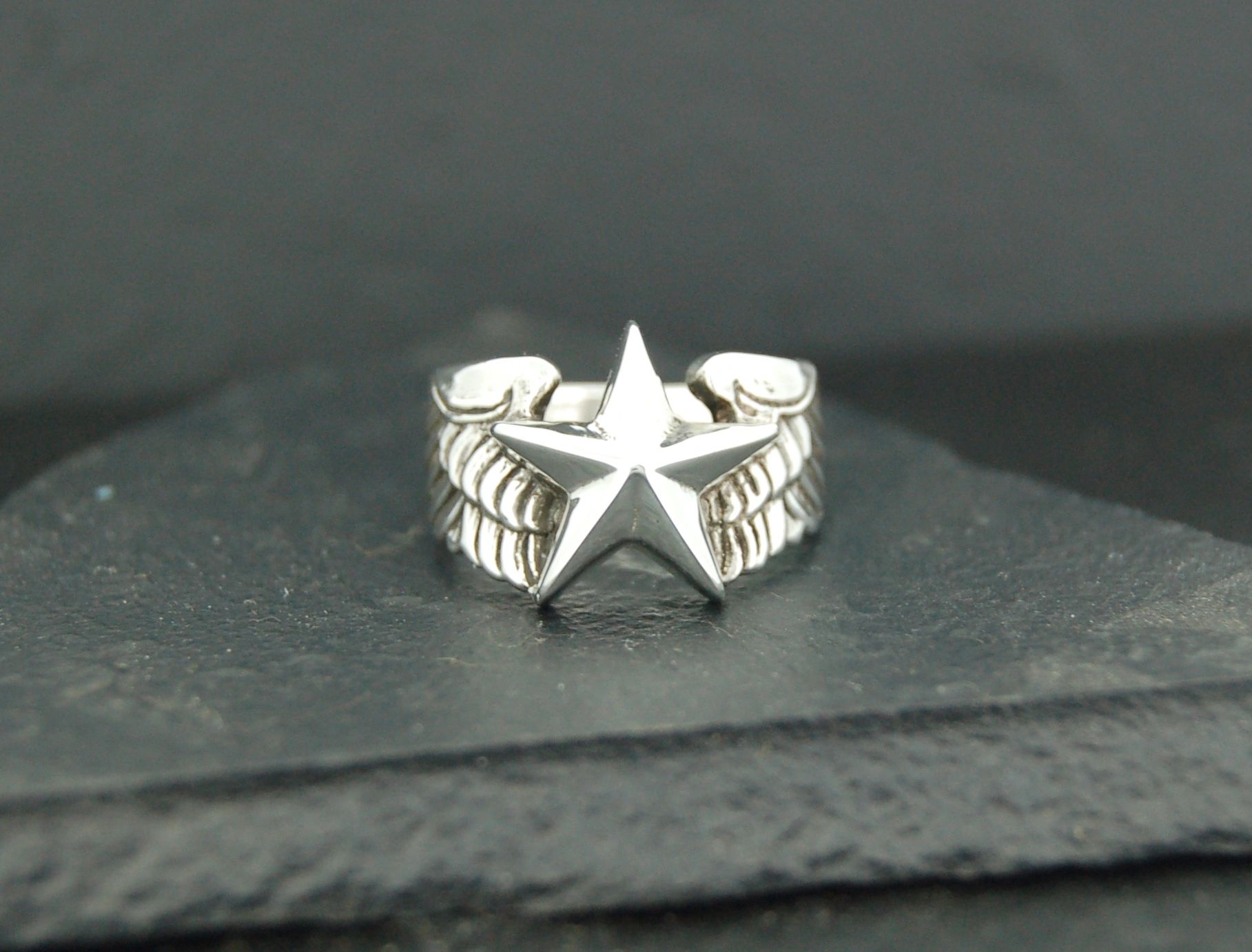 Silver ring with a prominent star design on a textured band.