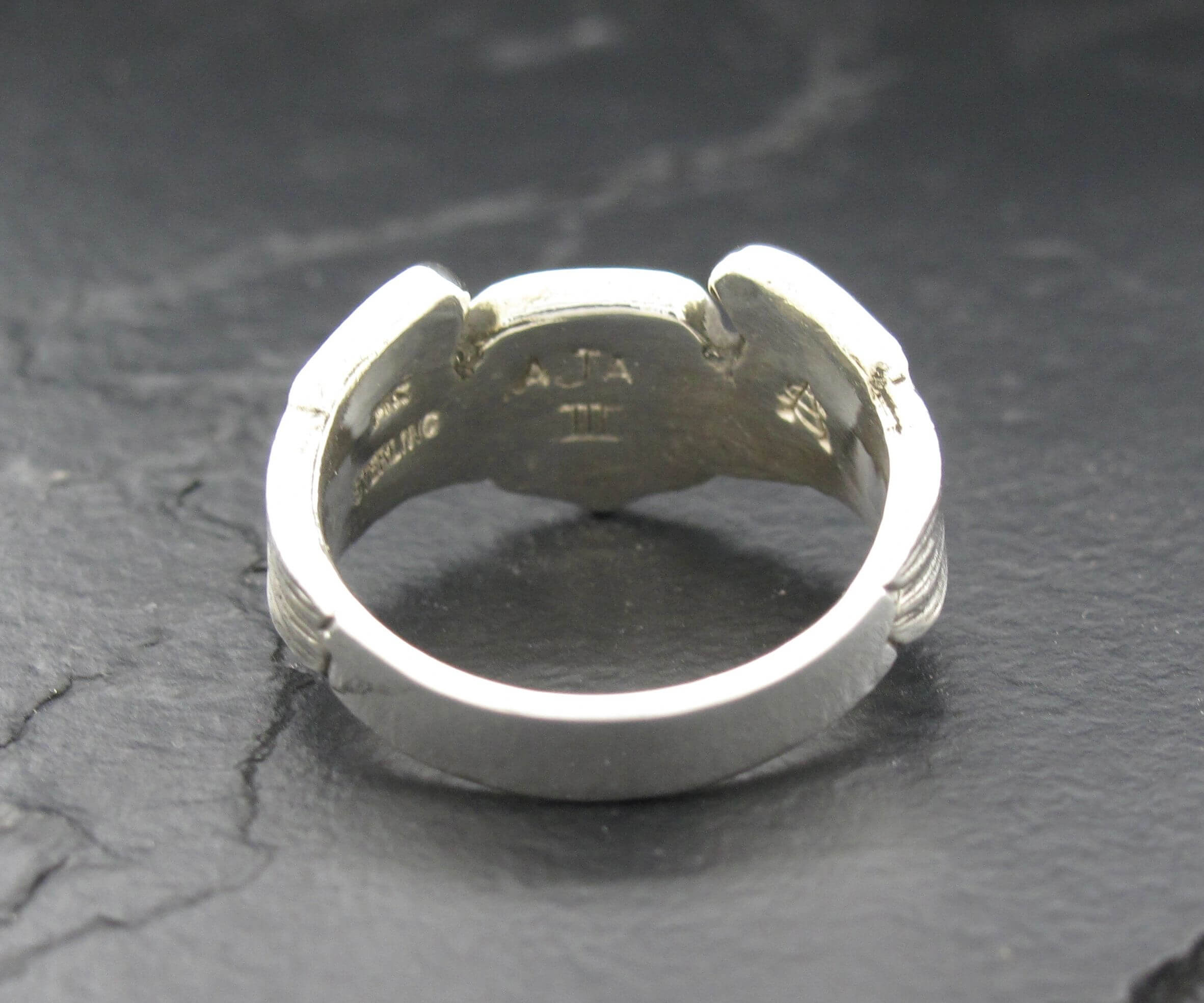 Close-up of a silver ring with an open design on a dark surface.