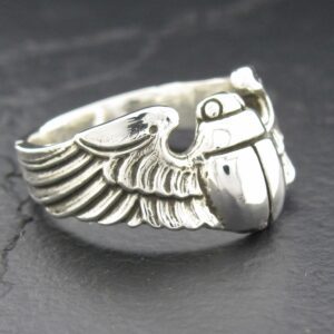 Close-up of a silver ring with detailed wing and grenade design.