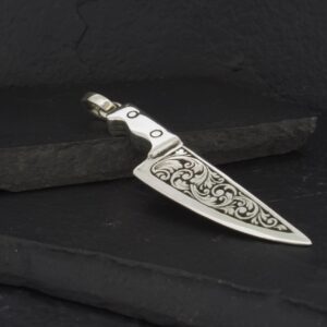 Intricately engraved metal knife with a detailed handle design.