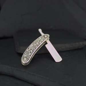 Intricately designed vintage straight razor with a floral pattern on the handle.