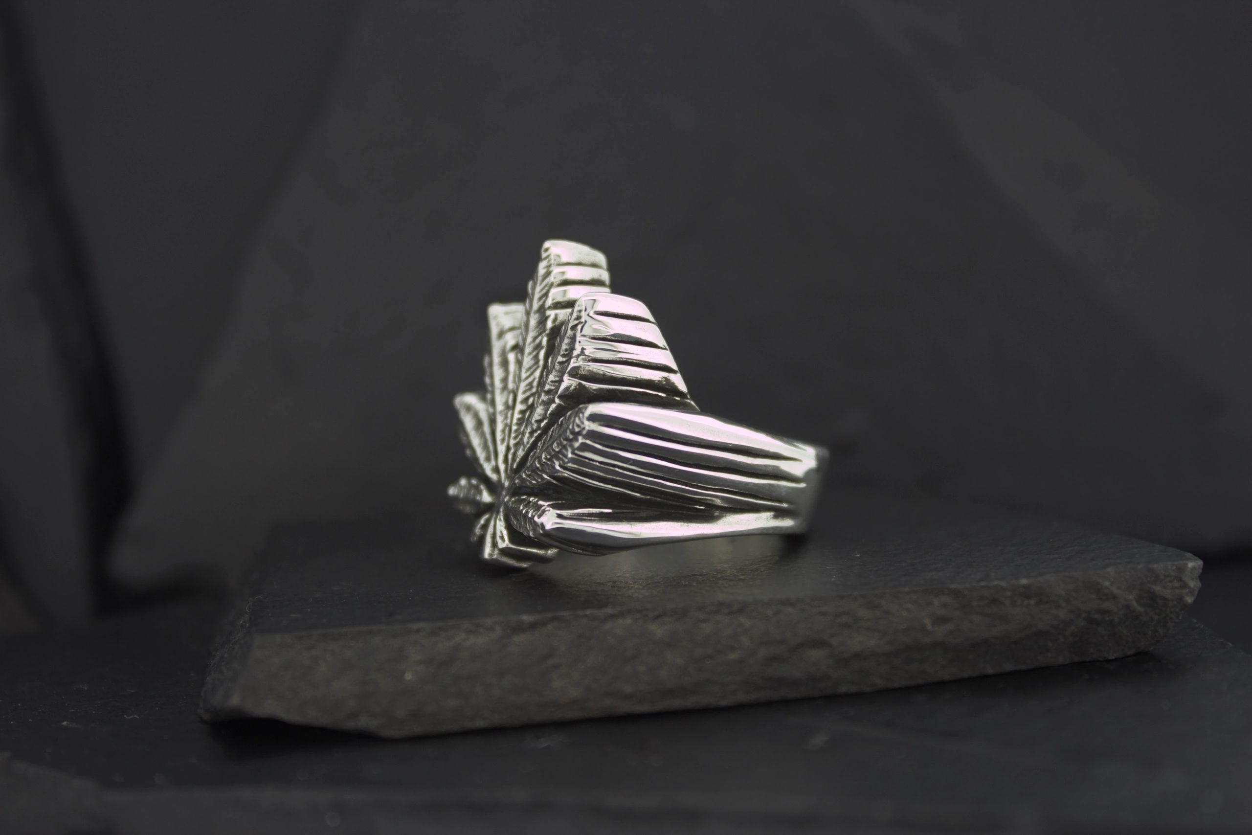 Art deco silver ring with geometric fan design on black background.