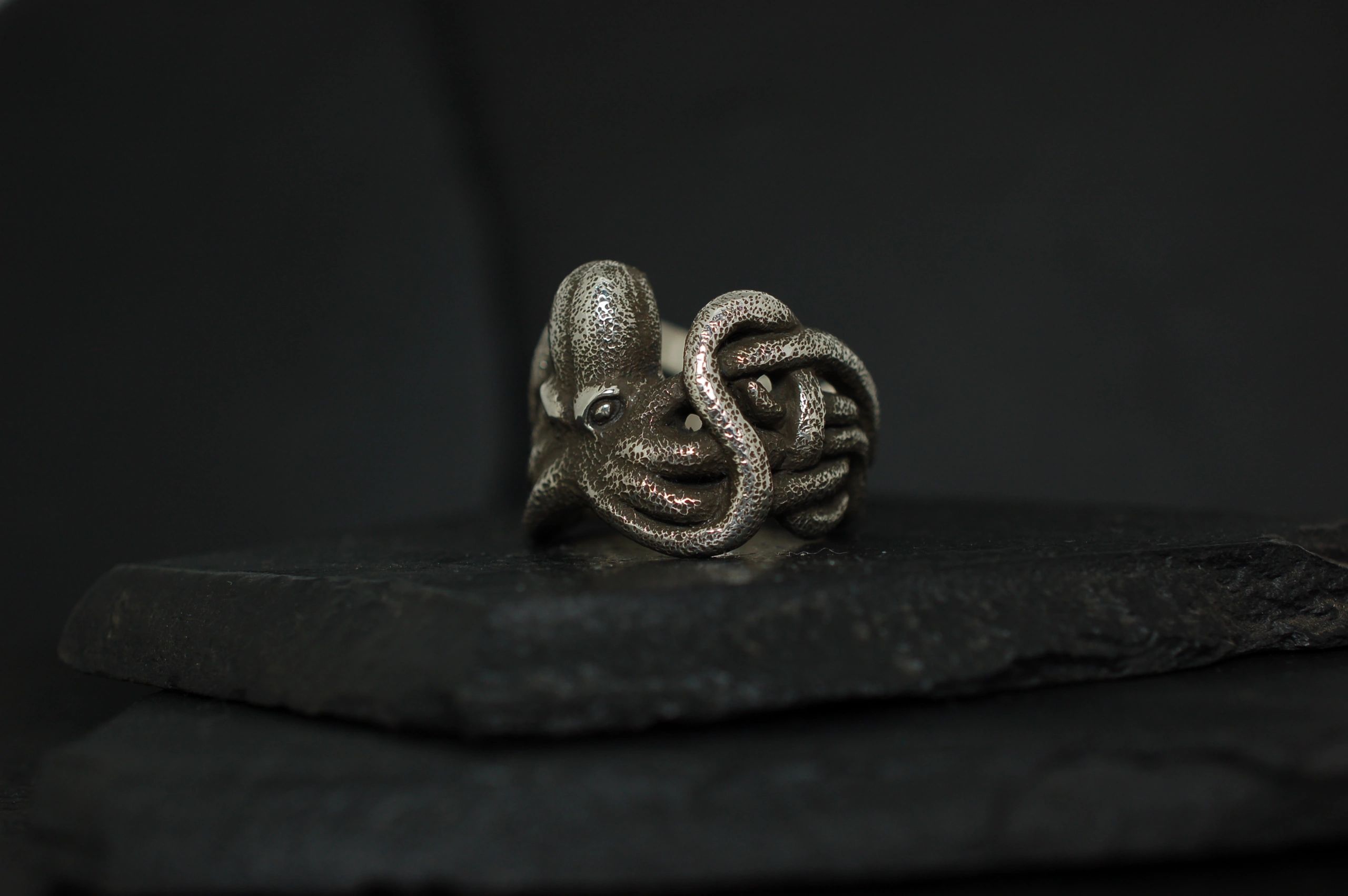 Intricately designed octopus ring with detailed tentacles on a dark background.