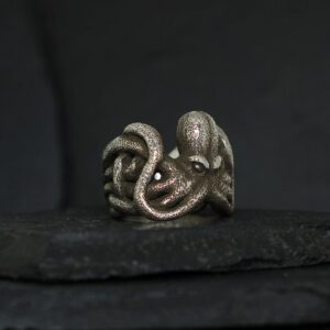 Intricately designed octopus ring on a dark surface.