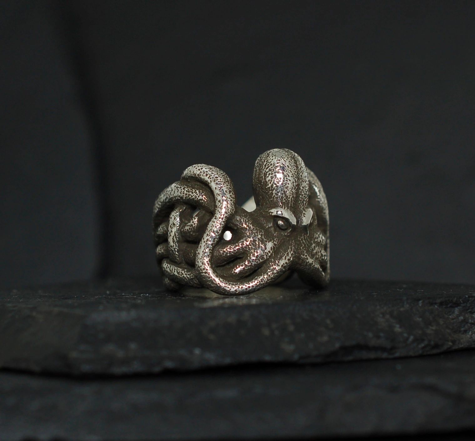 Intricately designed octopus ring on a dark surface.