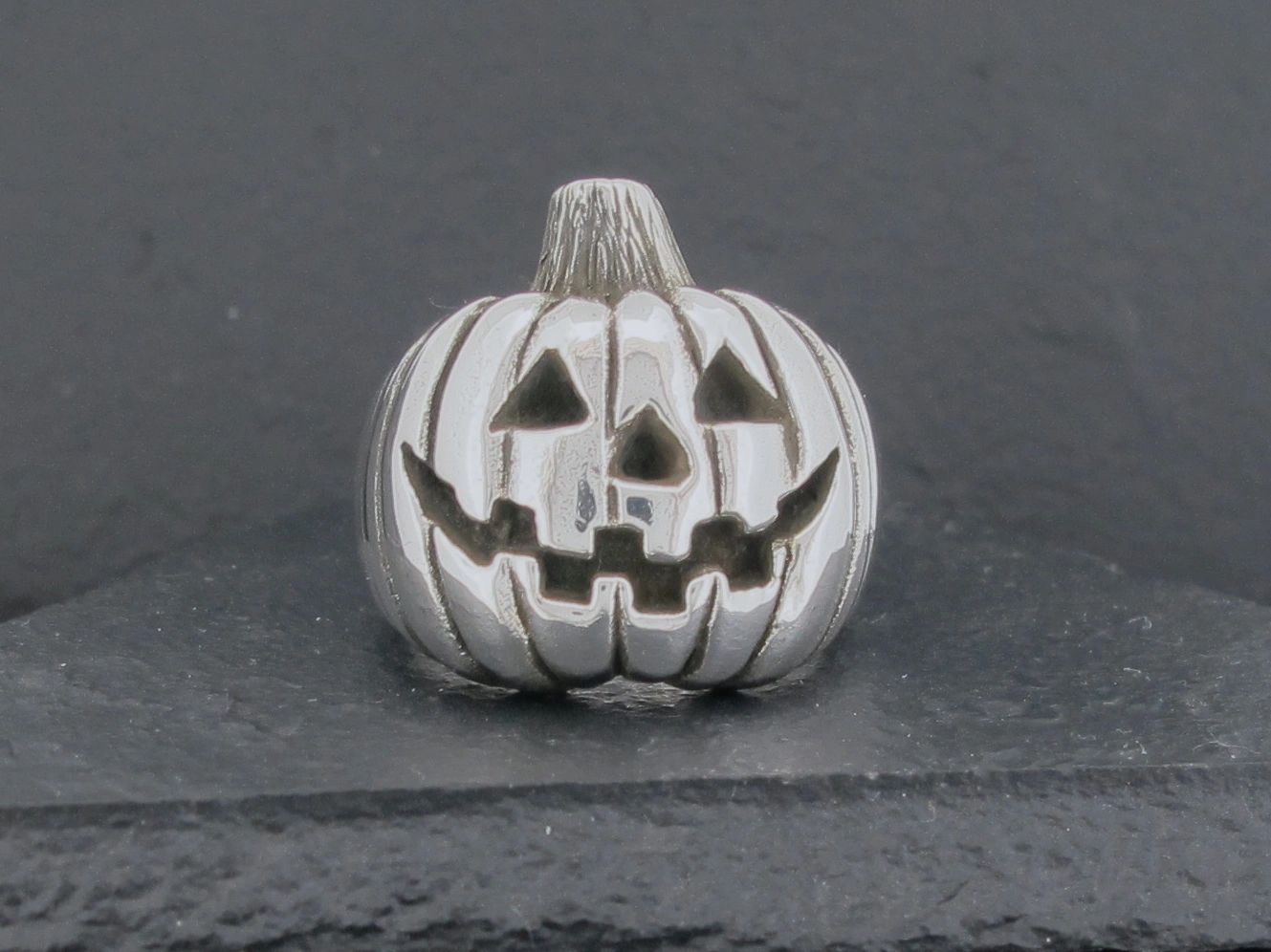 A small silver pumpkin with carved jack-o'-lantern face.