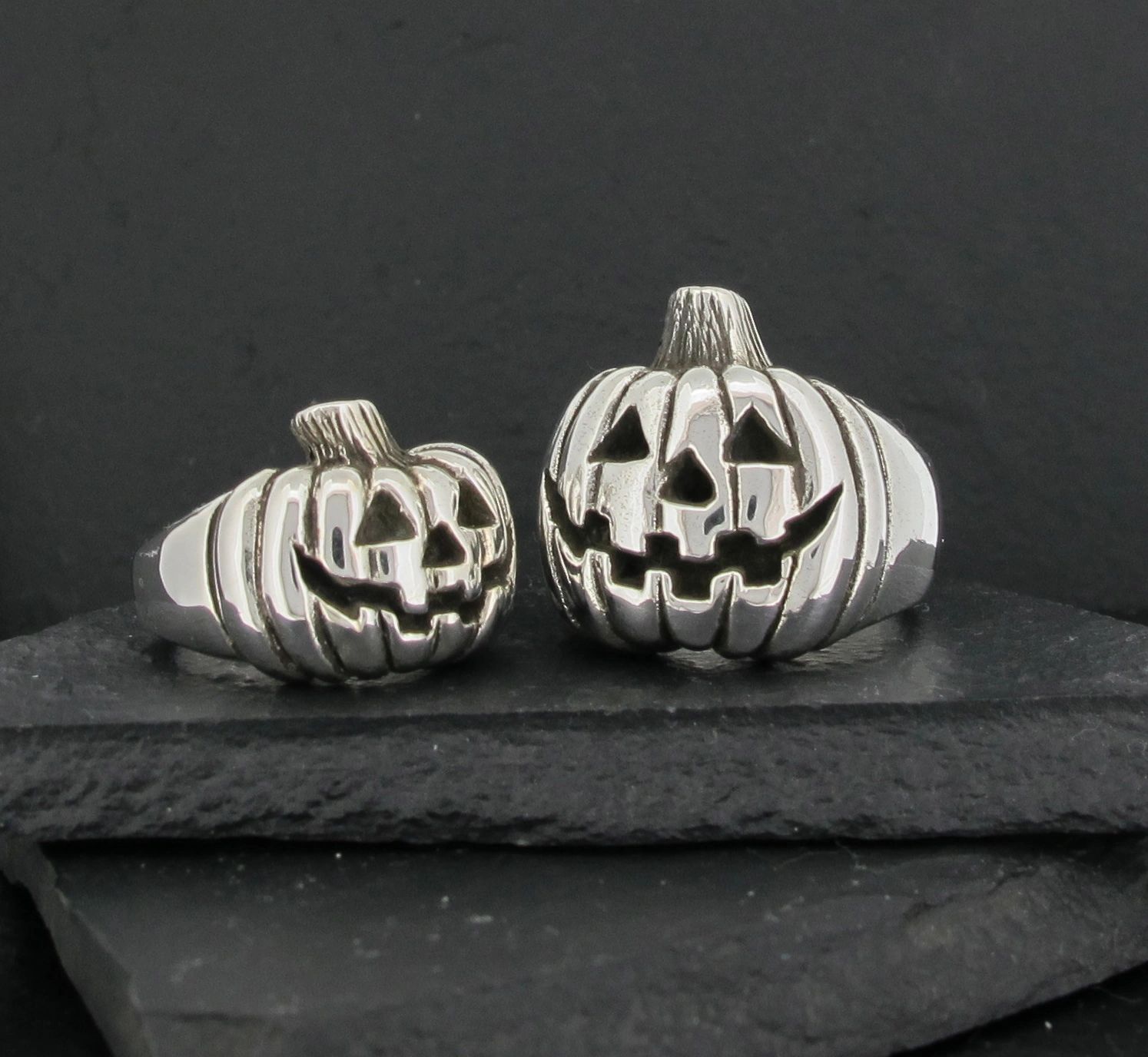 Two silver jack-o'-lantern pumpkin decorations on black stones.