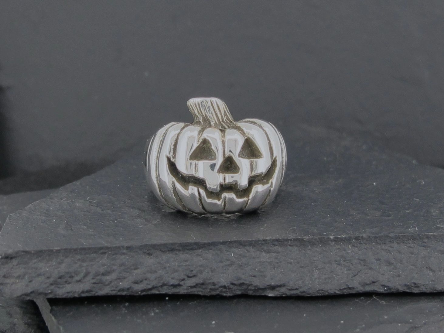 Silver pumpkin charm with a jack-o'-lantern face.