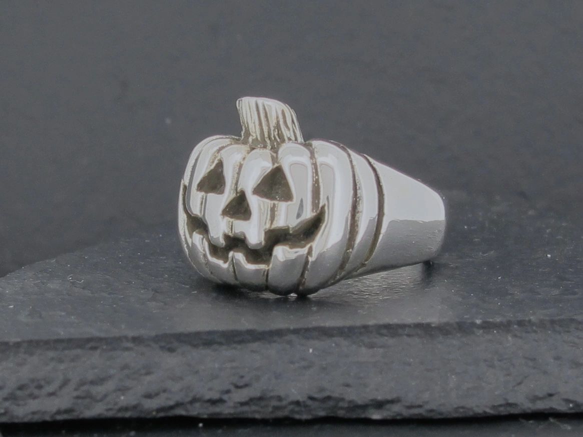 A silver ring featuring a carved jack-o'-lantern pumpkin design.
