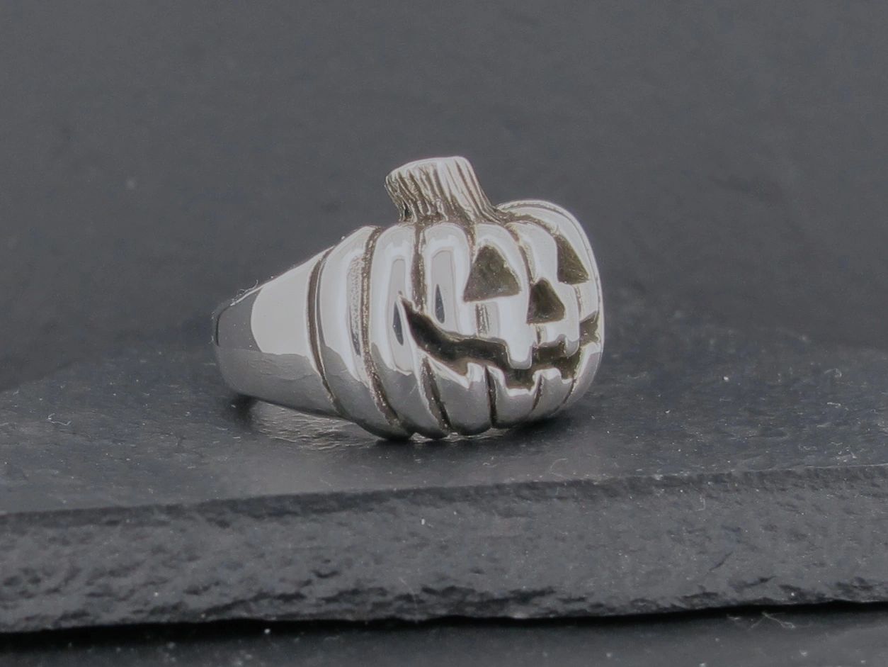 Silver ring shaped like a carved pumpkin with a smiling face.