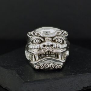 Intricately carved silver ring with a fierce mythical face design.