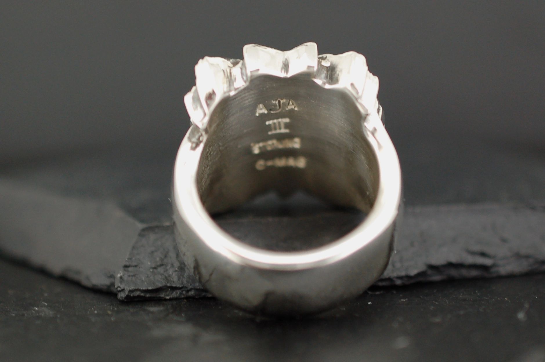 Close-up of a silver ring with engraved markings inside.