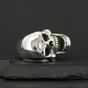 A polished silver skull ring with detailed features on a black background.