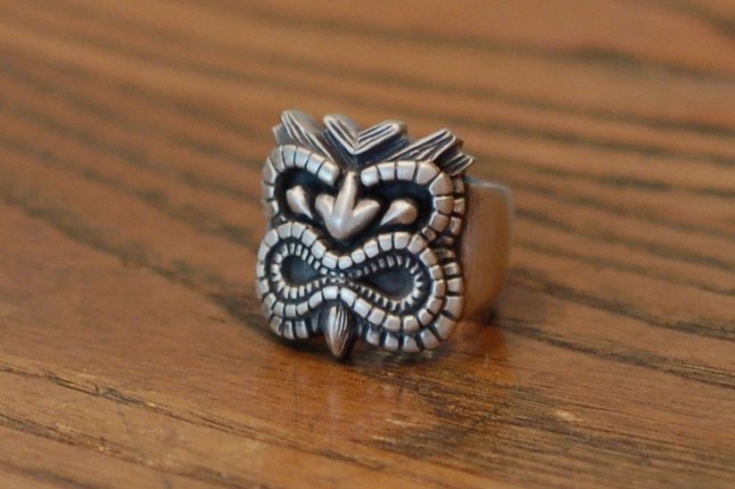 A silver ring with an intricate tribal design on a wooden surface.