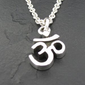 Silver Om symbol pendant on a chain against a dark background.