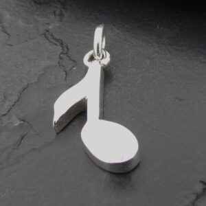 Silver pendant shaped like a musical note on a dark surface.